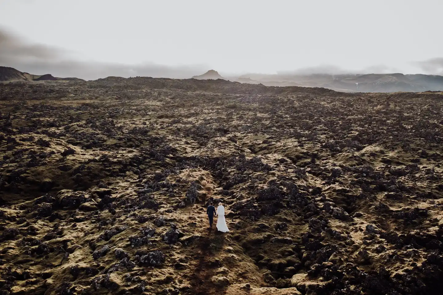 Couple eloping in a vast volcanic landscape